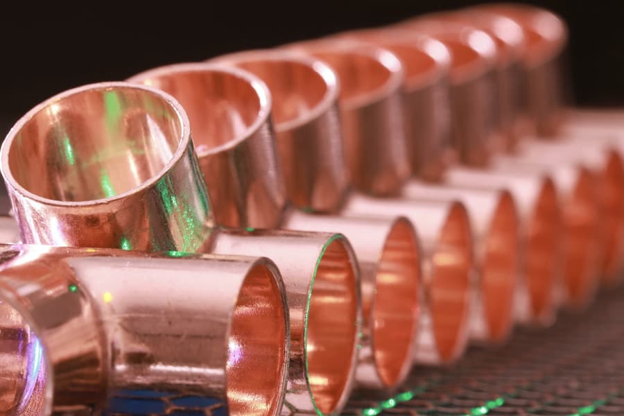Polished copper pipe fittings lined up on the workshop bench