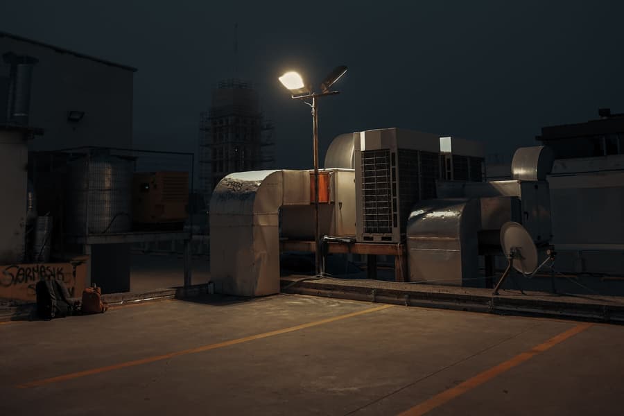 Rooftop condensing units under a single street light at night