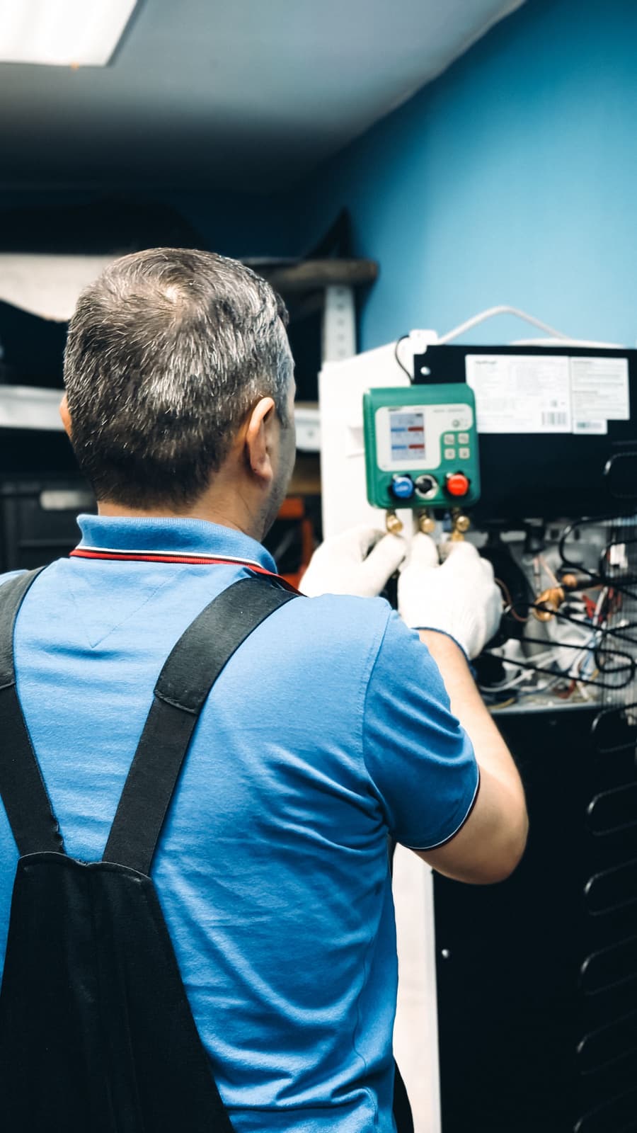 Technician in gloves checking a digital refrigeration controller