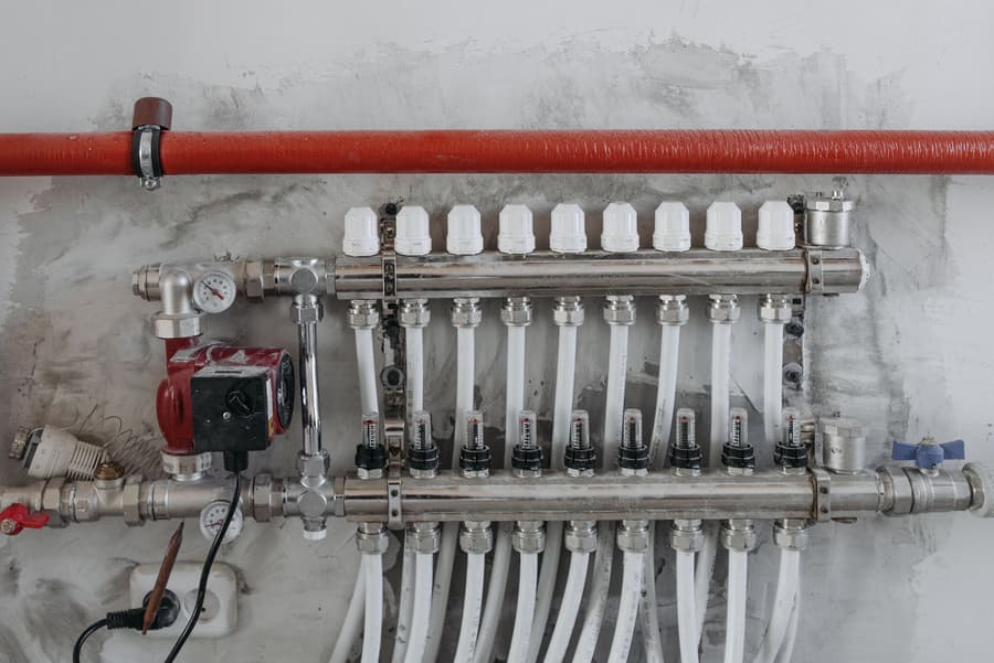 Hydronic manifold with pump and valves on a plant room wall